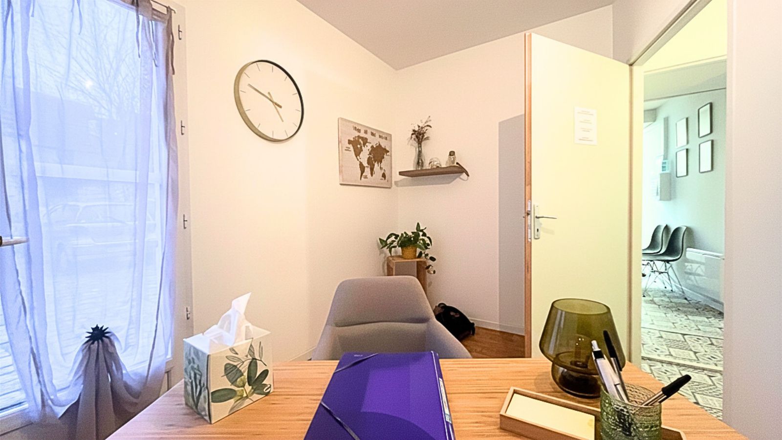 Le cabinet de consultation, fauteuil du patient face au bureau, salle d’attente au fond.
